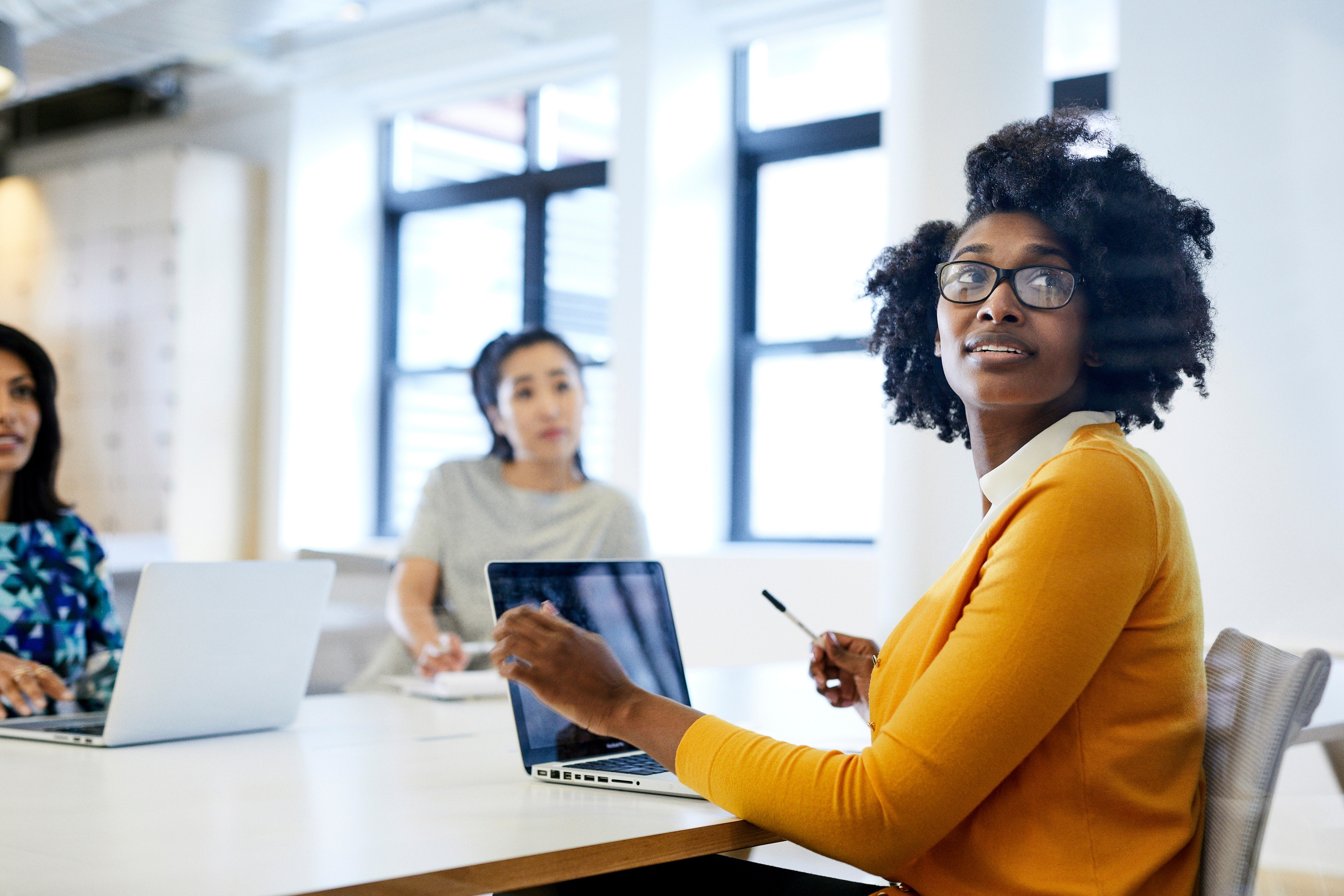 A young woman sits at a table with her computer studying in a group